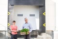 Portrait of owner with crate standing by female botanist against plant nursery