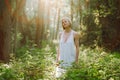 Portrait of pacified middle-aged woman standing in forest among plants, trees on sunny day, enjoying weather, posing.