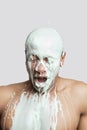 Paint falling on shirtless young Hispanic man`s head against gray background