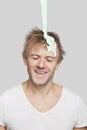 Portrait of Paint falling on young Caucasian man`s head against gray background