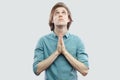 Portrait of palm hands handsome long haired blonde young man in blue casual shirt standing looking up and pray or begging to God