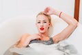 Portrait passionate young caucasian blonde girl lying in white bathroom