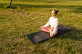 Portrait of peaceful young yogi woman sitting in lotus pose at city park on sunny summer morning at dawn. Calm female Royalty Free Stock Photo