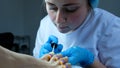 Portrait of a pedicurist applies a transparent fixative gel polish to the toenails