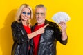 Portrait of pensioner beautiful handsome cheerful spouses demonstrating profit isolated over bright yellow color