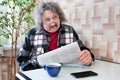 A portrait of a pensioner with a cup of coffee and a newspaper in His Hands a pensioner is reading a newspaper the meaning of