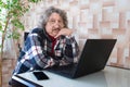 A portrait of a pensioner with a laptop in a room at home