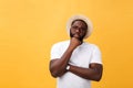 Portrait of a pensive afro american man in glasses looking up at copyspace isolated on a yellow background Royalty Free Stock Photo