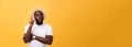 Portrait of a pensive afro american man in glasses looking up at copyspace isolated on a yellow background Royalty Free Stock Photo