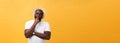 Portrait of a pensive afro american man in glasses looking up at copyspace isolated on a yellow background Royalty Free Stock Photo