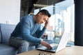 Pensive asian man working in office on laptop, anxious business man in modern office, frustrated depressed