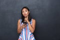 Portrait of a pensive asian woman in dress standing isolated over gray background, Royalty Free Stock Photo