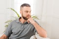 Portrait of pensive bearded man sitting on sofa and looking away