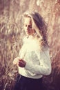 Portrait of pensive beautiful young blonde girl in a field in white pullover, the concept of health and beauty