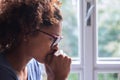 Portrait of pensive black woman standing beside window