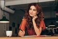 portrait of pensive blogger sitting at table with notebook