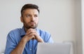 Portrait Of Pensive Businessman Sitting At Workplace With Laptop And Looking Away Royalty Free Stock Photo