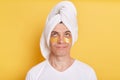 Portrait of pensive confused man wearing white t shirt and towel, having cosmetic patches under his eyes, looking up with puzzled Royalty Free Stock Photo