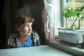 Portrait of pensive elderly woman sadly looking out the window. Royalty Free Stock Photo
