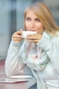 Portrait of a pensive girl drinking coffee and looking outdoors through a window Royalty Free Stock Photo