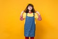 Portrait of pensive girl teenager in french beret, denim sundress holding hair, looking up isolated on yellow wall Royalty Free Stock Photo