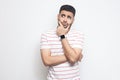 Portrait of pensive handsome bearded young man in striped t-shirt standing, touching his face, looking aside away and thinking Royalty Free Stock Photo