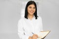 Portrait of a pensive pretty woman making notes in notepad and looking at the camera isolated over white background Royalty Free Stock Photo