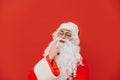 Portrait of a pensive Santa Claus standing on a red background and looking away and thinking. Christmas and New Year Royalty Free Stock Photo