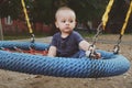 Pensive one year old toddler swings on a swing. Royalty Free Stock Photo