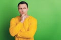 Portrait of pensive unsure guy finger chin think make decision on green background