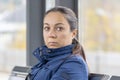 Portrait of a pensive woman 40-45 years old, sitting in a glass bus stop, waiting for a bus, looking away. Royalty Free Stock Photo