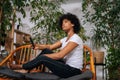 Portrait of pensive young African American woman listening music from mobile phone, thinking looking away sitting on Royalty Free Stock Photo