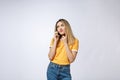 Portrait of a pensive young asian woman holding mobile phone and looking away thinking over white background Royalty Free Stock Photo