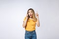 Portrait of a pensive young asian woman holding mobile phone and looking away thinking over white background Royalty Free Stock Photo