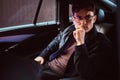 A pensive young man wearing glasses sitting in the back seat of the car. Royalty Free Stock Photo