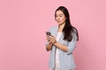 Portrait of pensive young woman in striped jacket using mobile phone, typing sms message isolated on pink pastel Royalty Free Stock Photo