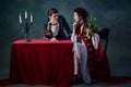 Portrait of people in image of vampires over dark green background. Man with burger, woman with celery. Health and junk