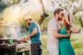 Portrait of perfect caucasian couple kissing at barbecue party, friends having a good time and cooking on background