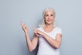 Portrait of perfect, nice, old, smiling woman in t-shirt demonstrate, choosing, pointing with two forefingers to copy space, look Royalty Free Stock Photo