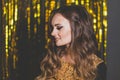 Portrait of perfect young brunette woman with makeup and long wavy brown hair smiling on golden party background Royalty Free Stock Photo