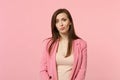 Portrait of perplexed puzzled young woman wearing jacket standing and looking camera isolated on pastel pink wall Royalty Free Stock Photo