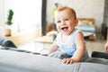 Portrait of a persistent funny little baby boy sitting on gray sofa and smiling or laughing