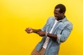 Portrait of persistent young man pretending to hold rope in hands and pull. indoor studio shot isolated on yellow background