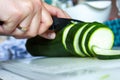A portrait of a person cutting a zucchini with a sharpp knife in a kitching while cooking a nice and delicious dinner. The Royalty Free Stock Photo