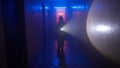 Portrait of person in the hallway with neon light. Person in chemical protection suit with flashlight walking down the