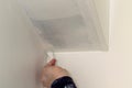 A portrait of a person painting the corner between a wall and the ceiling of a room in a house. The hand of the person is holding Royalty Free Stock Photo