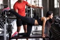 Trainer coach stretching leg to girl in gym