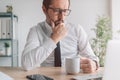 Portrait of perturbed businessman with cup of coffee in the office looking at laptop computer screen Royalty Free Stock Photo