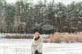 Portrait of petty young blond woman, dressed warmly, with a scarf and mittens. Beautiful girl enjoying in the snow Royalty Free Stock Photo