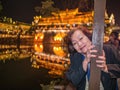 Portrait photo of Asian senior woman with beautiful nightscape of fenghuang old town.